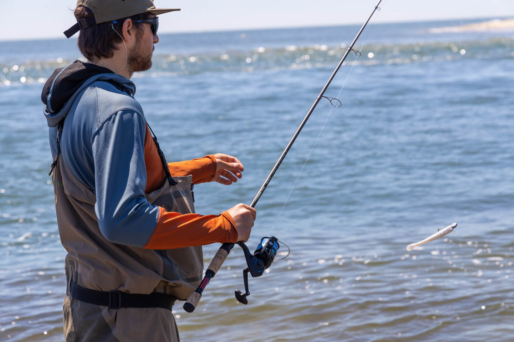 Angler holding onto his fishing pole and his lure is dangling up in the air.