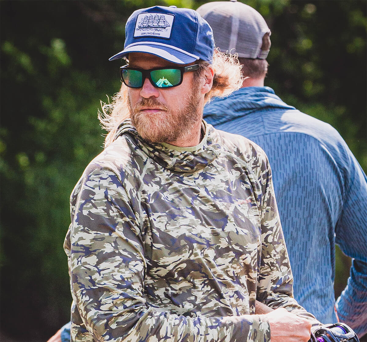 Brian Porter is wearing a cameo shirt and sunglasses, while looking down to his right