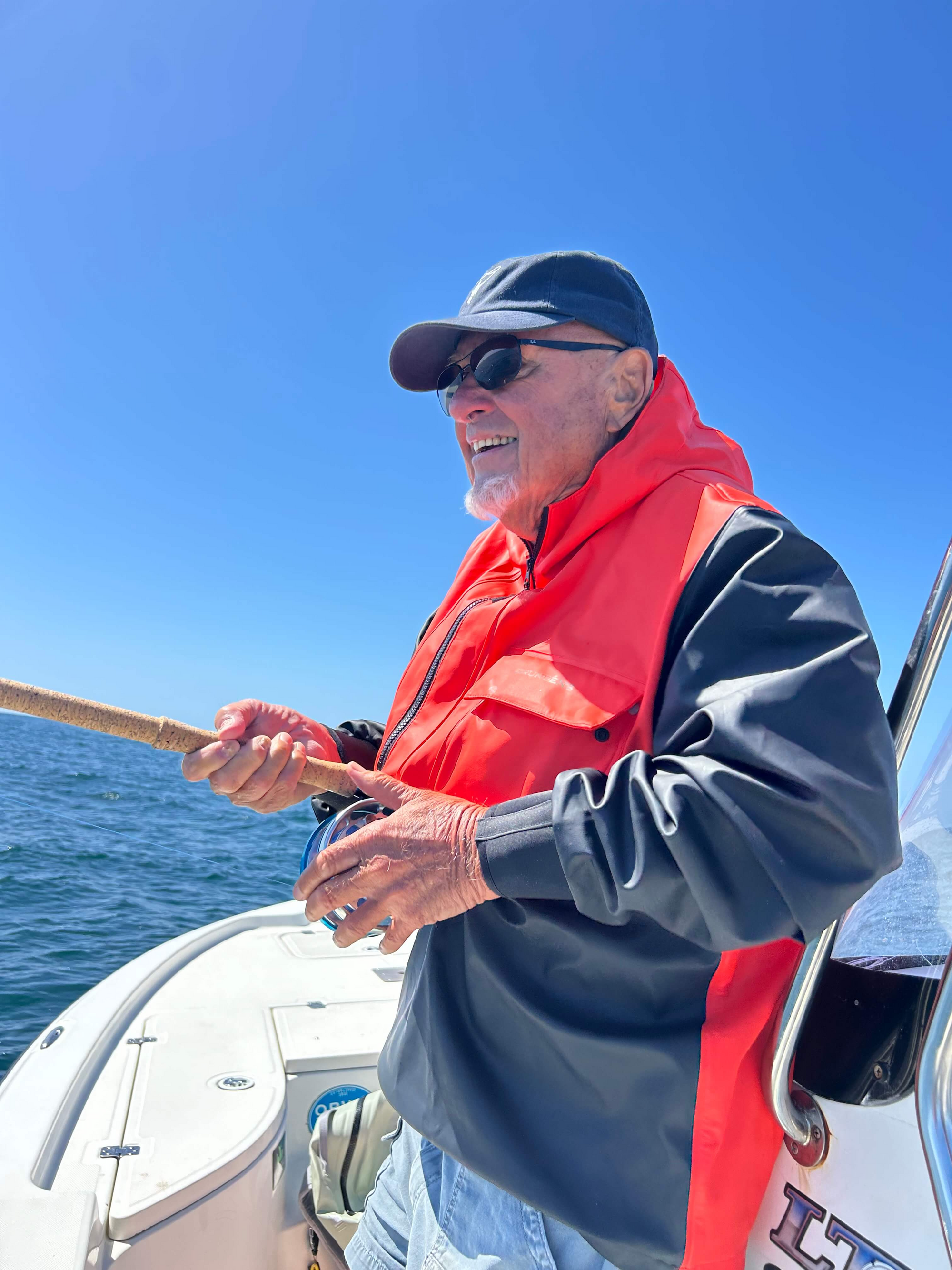 Nick Curcione is back of a boat and holding onto a fly rod.