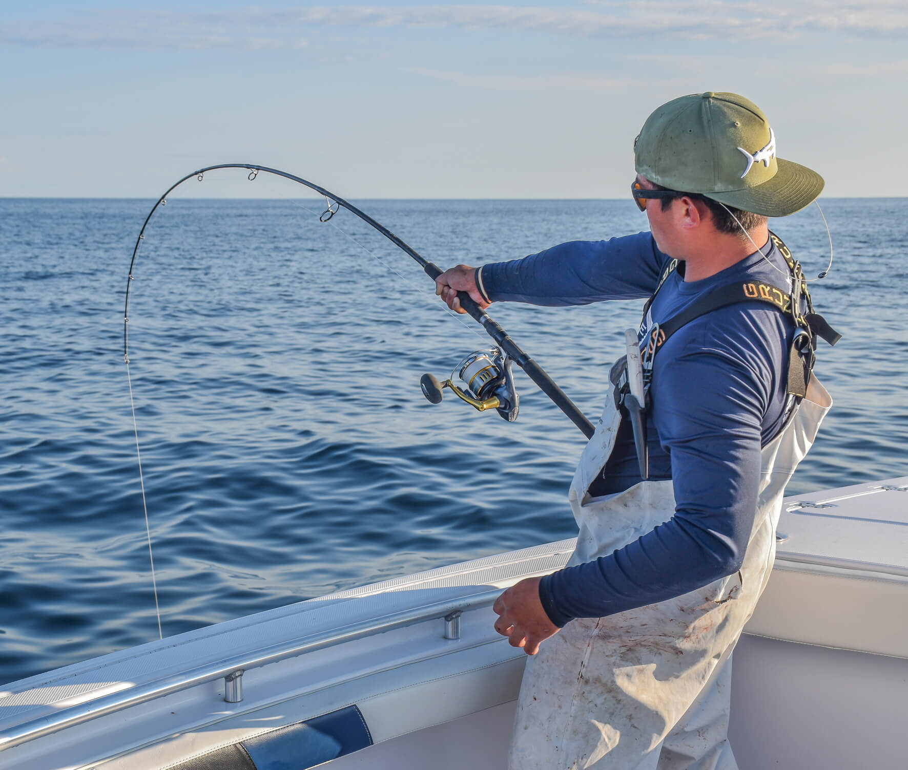 An angler is holding onto his fishing pole, which is bending