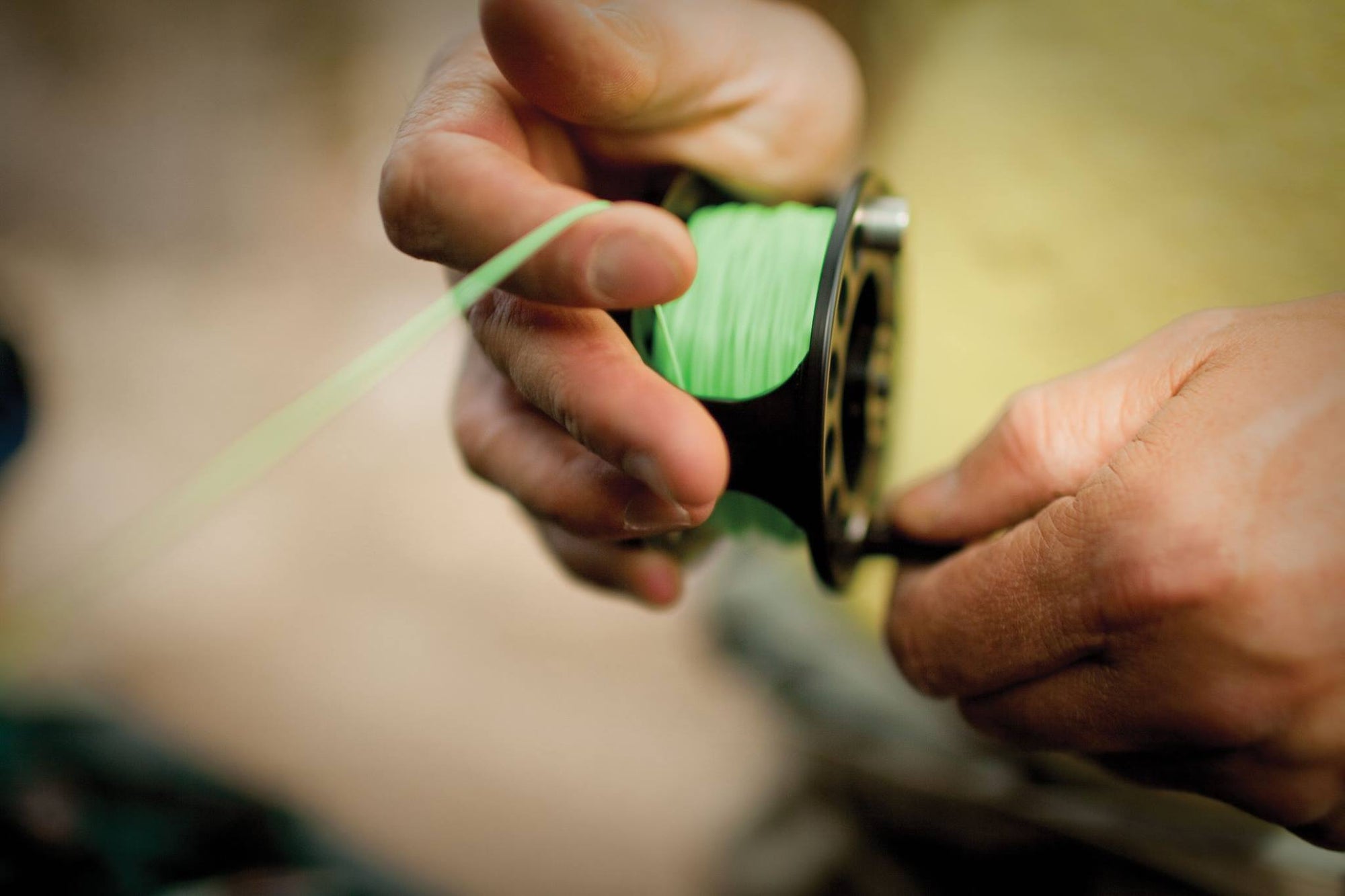A pair of hands spooling their fly reel with 444 Series SL fly line