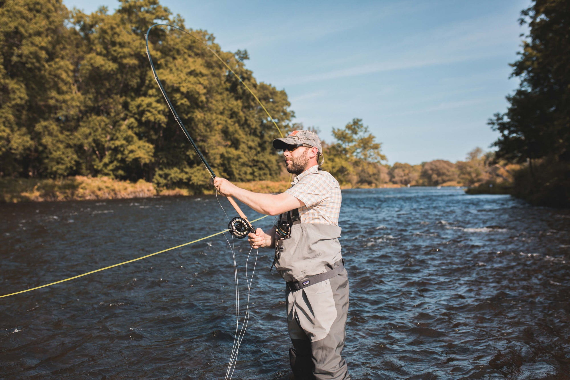 Brooks fly fishing on the salmon river. He is standing in knee high water and is about to cast his line out 