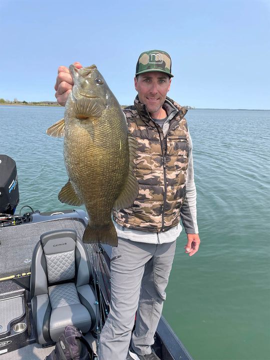 Travis Manson is holding up a fish on a boat
