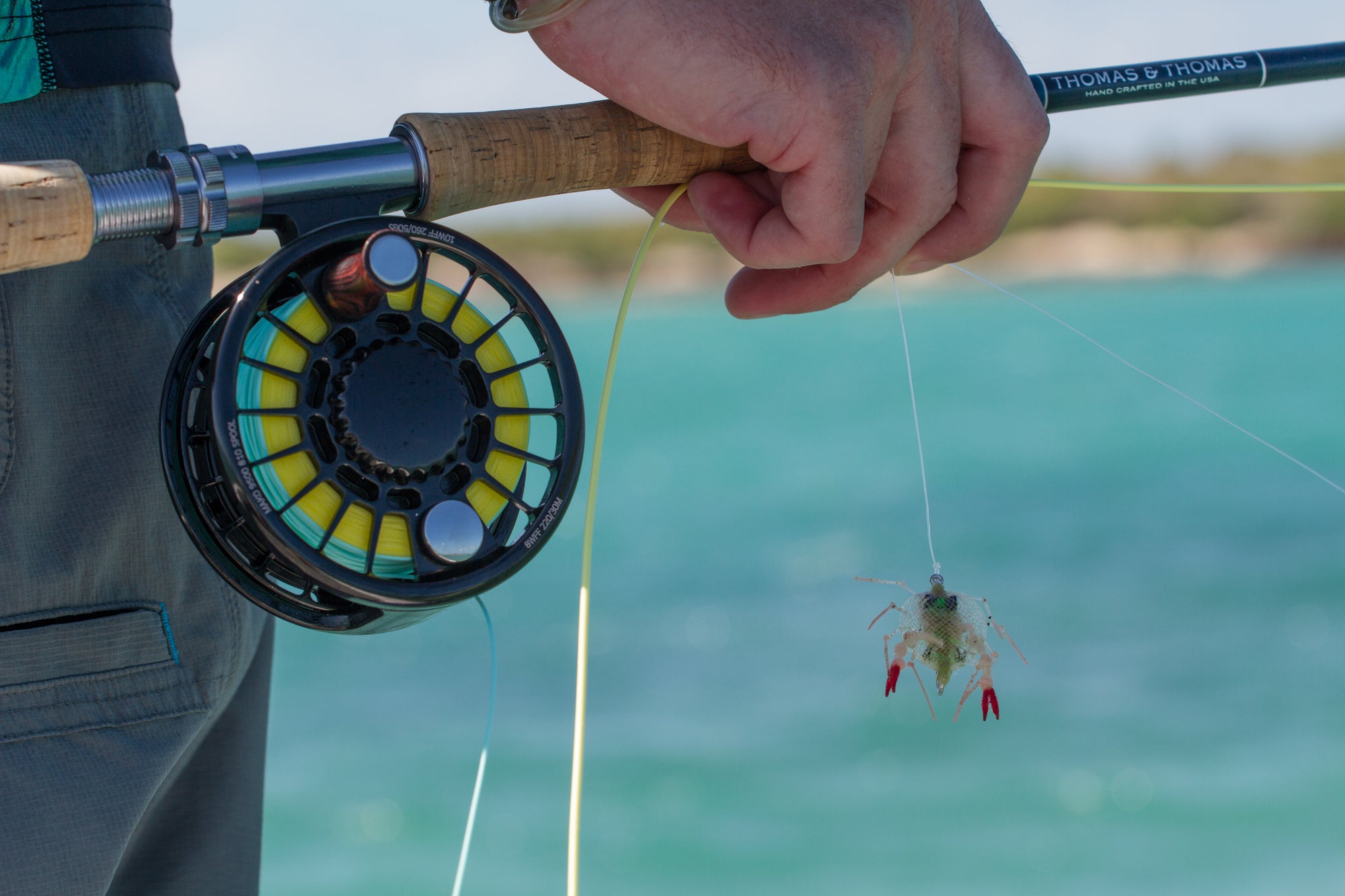 Fishing rod with fly reel and fishing lure over a blurred water background
