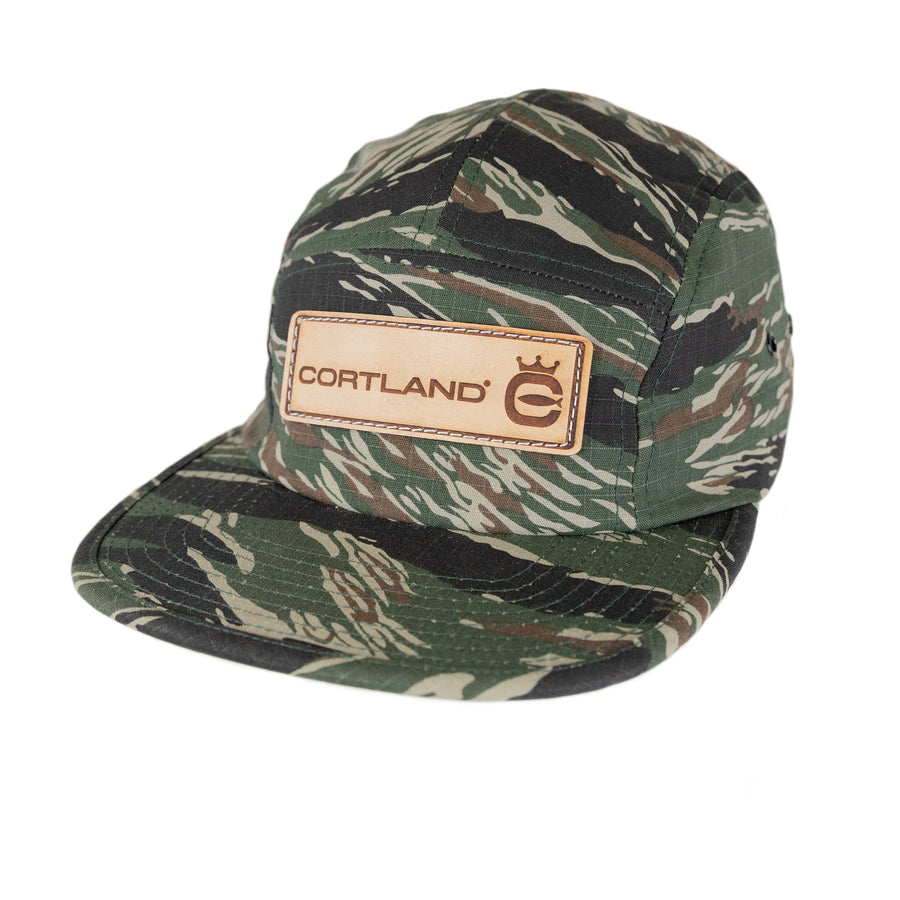 Cortland Jungle Cap. The hat is camo and has a leather patch on the front. The patch has Cortland and the Cortland logo. 