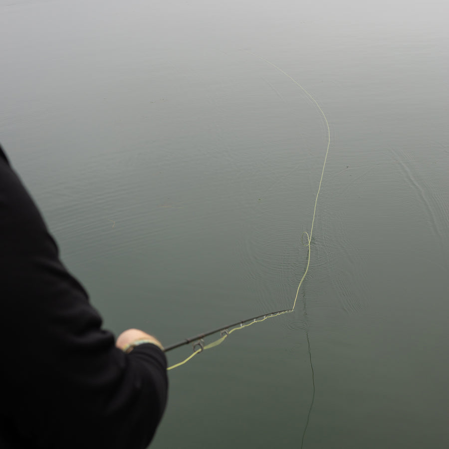 A fly line sitting on a body of water with the angler's shoulder in the bottom left of the frame. 