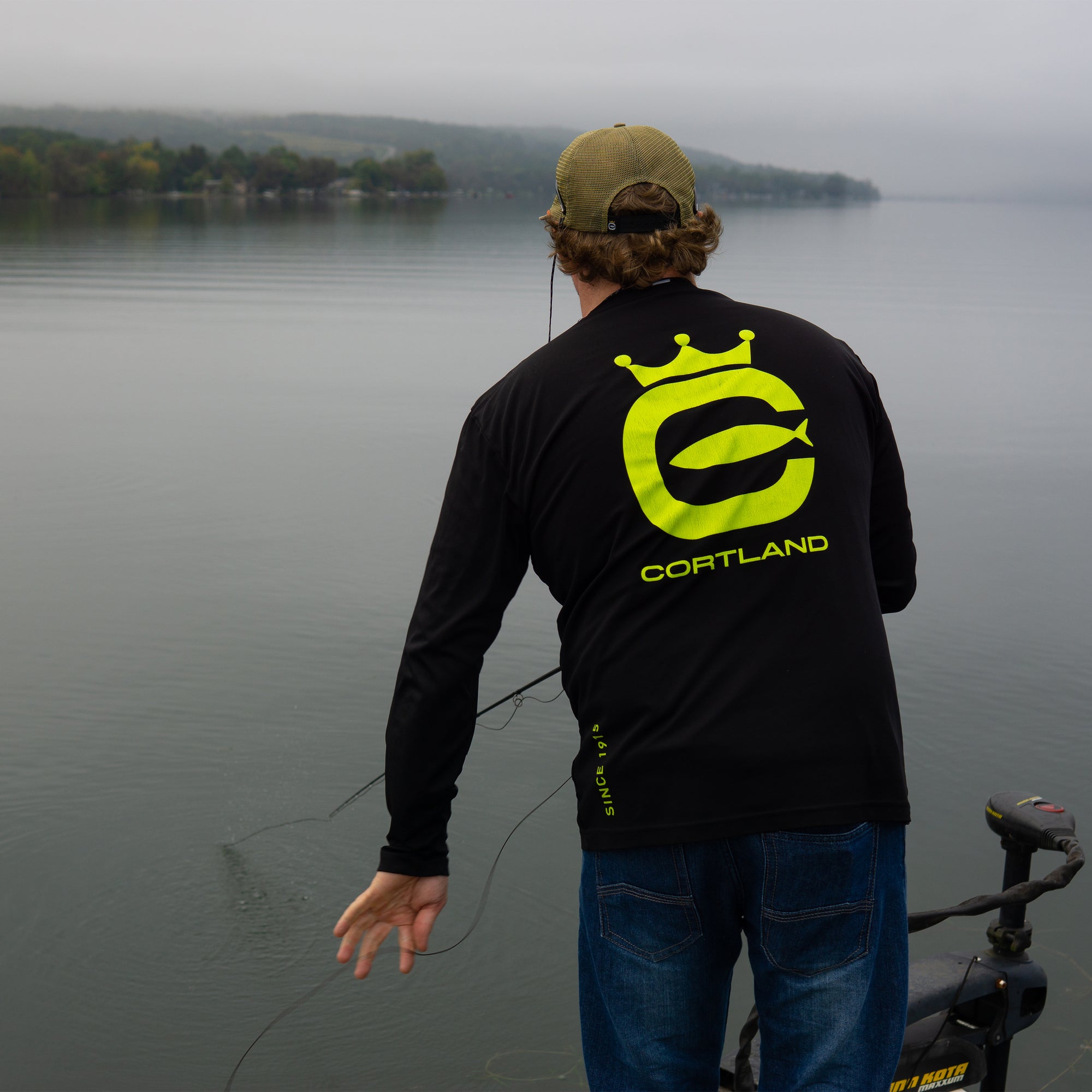 Fisherman has his back turned to the camera while he is fly fishing. 