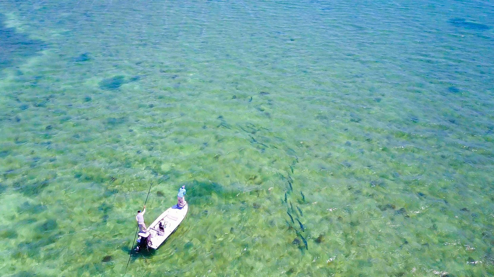 Aerial shot of two individuals fishing on a small boat.